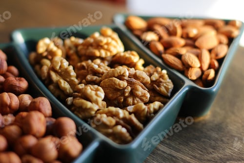 Preview: different types of nuts. snacks for the New Year table in a plate in the shape of a Christmas tree.