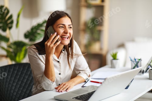 Preview: Young happy woman talking on the phone in the office
