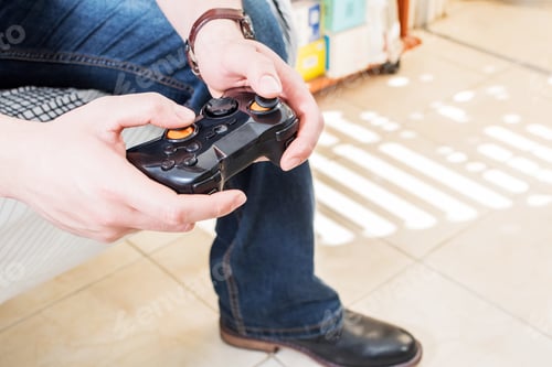 Preview: Closeup of a man's hand holding a game console while playing video games at home