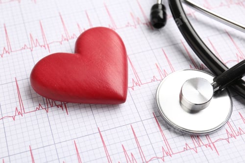 Preview: Cardiology. Stethoscope and red decorative heart on paper with cardiogram, closeup