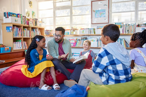 Preview: Teacher reading book to his little students in a library