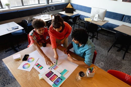 Preview: Creative multiracial design professionals discussing over color swatch at table in office