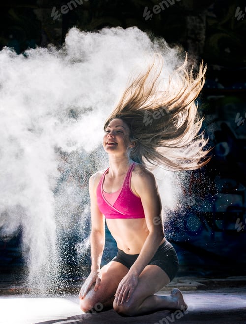 Preview: Woman kneeling throwing powder covered hair back smiling
