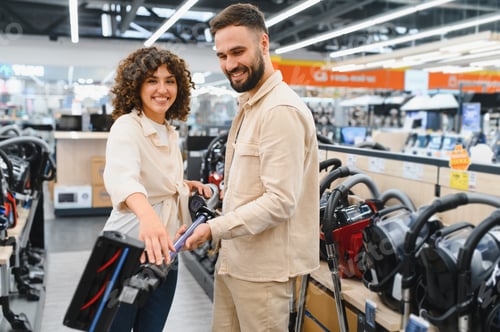 Preview: Happy couple choosing vacuum cleaner in electronics store