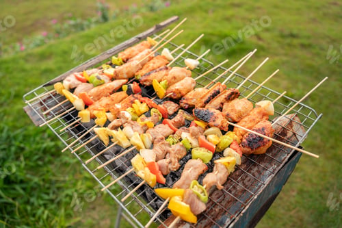 Preview: Assorted delicious grilled meat with vegetables on barbecue grill with smoke and flames. Grilling