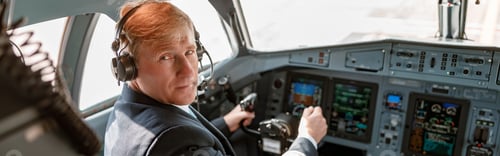 Preview: Male pilot in headphones sitting in airplane cockpit