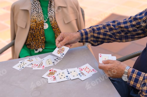 Preview: Hands of two elderly people in the garden of a nursing home or retirement home playing cards