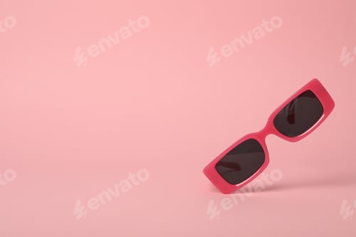 Vista previa: Gafas rosas con lentes oscuras sobre fondo rosa, espacio para texto