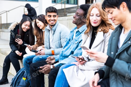 Preview: Happy group of friends in the city using mobile phones and laughing together