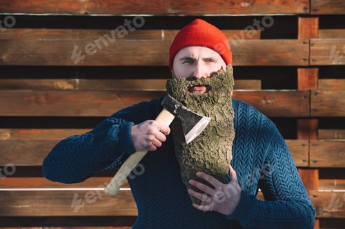 Preview: young man with beard made of wood bark and axe in hand outdoors