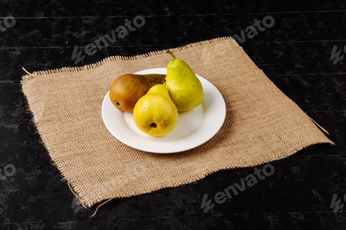 Preview: side view of fresh ripe pears on a plate on sackcloth