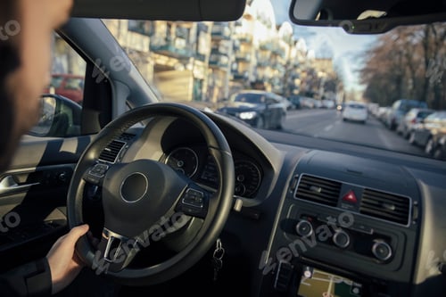 Preview: Steering wheel and hand of a man driving a car through the city