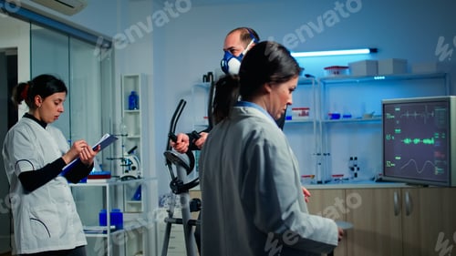 Preview: Doctor scientist looking at monitor with EKG reading while man with mask running