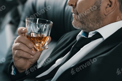 Preview: close-up shot of mature businessman with glass of whiskey
