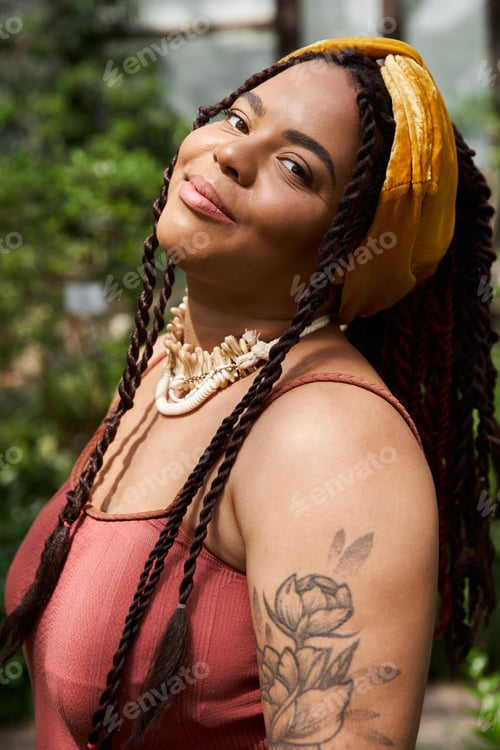 Preview: Bright smile of a woman amidst lush greenery in a vibrant greenhouse setting