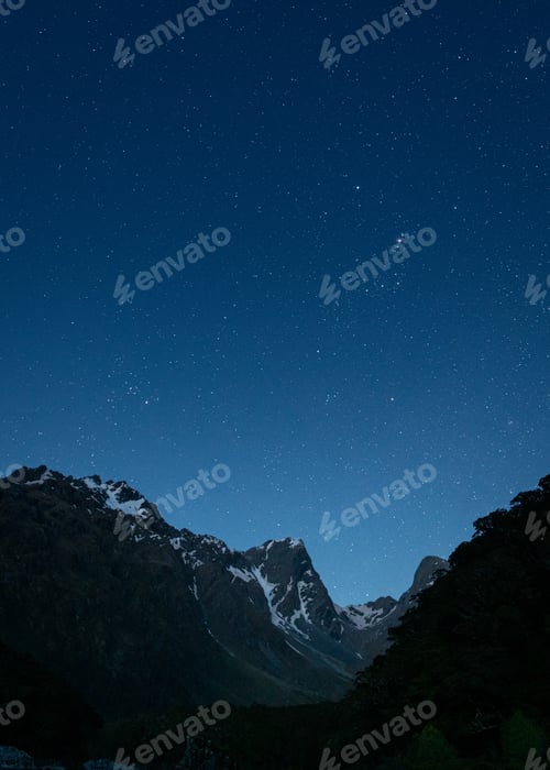 Preview: Vertical shot of mountains under a dark blue sky filled with stars