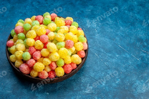 Preview: Close up view of delicious coloured sweets in a small brown pot on the right side on blue