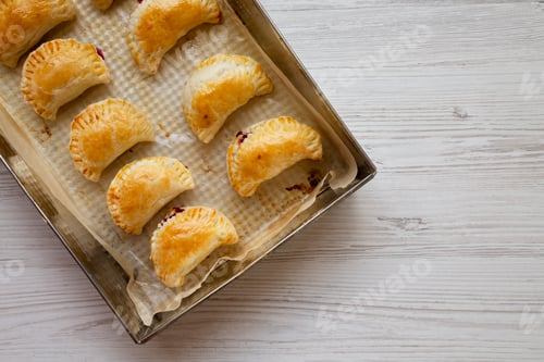 Preview: Homemade Cherry Hand Pies in a baking pan, top view. Flat lay, overhead, from above. Space for text.