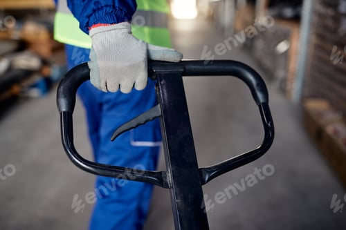 Preview: Close up of worker pulling pallet jack while working in warehouse.