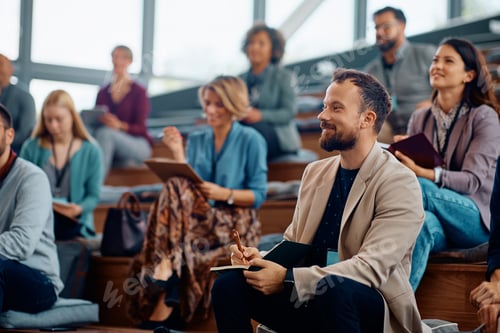 Preview: Happy entrepreneur taking notes while attending a business seminar in conference hall.