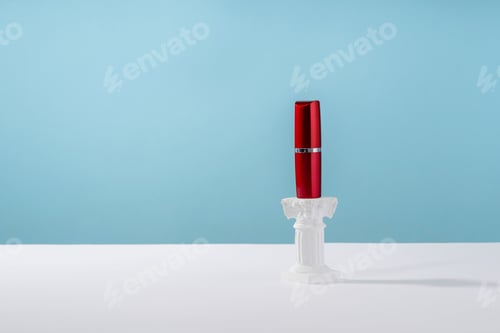 Preview: Red lipstick on roman marble column on blue background. Creative product stage mock up, cosmetic