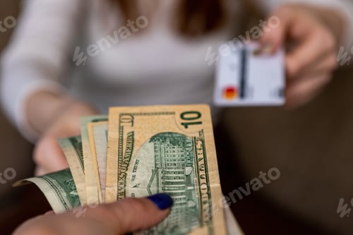 Preview: Exchange of a bank card for money. A woman's hand holds out a plastic bank card, and e is given doll