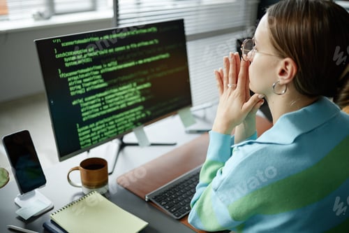 Preview: Young Woman Analyzing Code on Computer Monitor in Modern Office