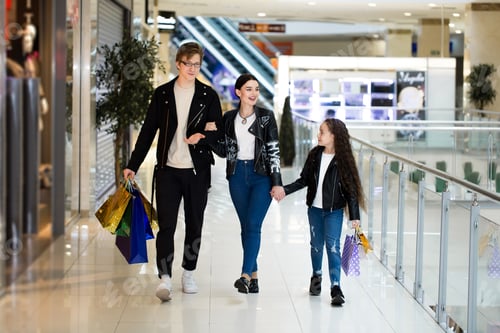 Preview: Happy young family with paper bags shopping at the Mall. Shop Windows with clothes