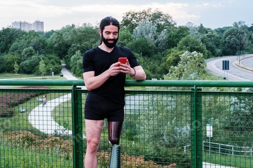 Preview: Young man with prosthetic leg attending to his smartphone
