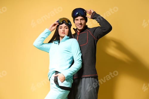 Preview: Couple wearing stylish winter sport clothes on yellow background