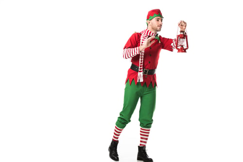 Preview: man in christmas elf costume holding red lantern and looking away isolated on white