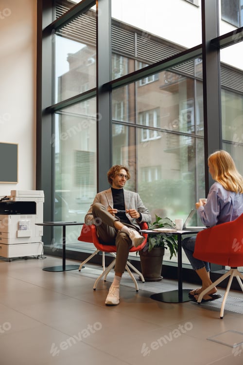 Preview: Two diverse business colleagues working together on project sitting in modern coworking