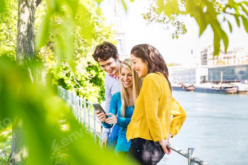 Preview: Friends laughing and sharing content on smartphone outdoors