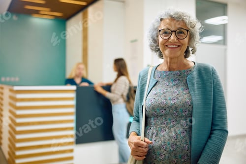 Preview: Happy senior female patient at medical clinic looking at camera