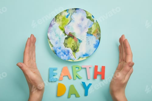 Preview: top view of woman holding colorful paper letters and planet picture on turquoise background, earth