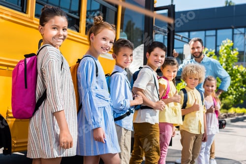 Preview: queue of happy pupils standing near school bus with teacher