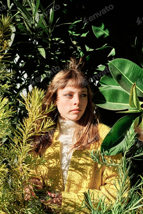 Preview: Portrait of a young blonde caucasian girl with blue eyes among the green plants of the park