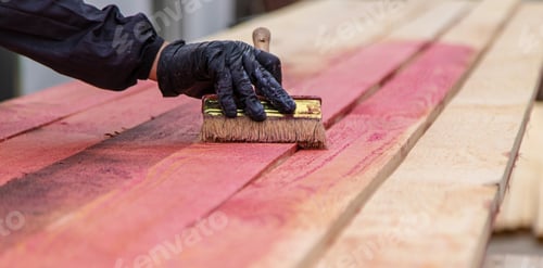 Preview: A man treats a board with a red antiseptic. selective focus.