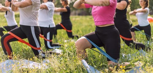 Preview: Group of women doing fitness on the grass with rubber bands