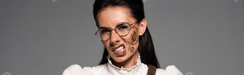 Preview: panoramic shot of irritated steampunk woman in glasses with makeup looking at camera isolated on