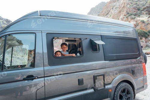 Preview: Two boys looking out of a gray camper van window