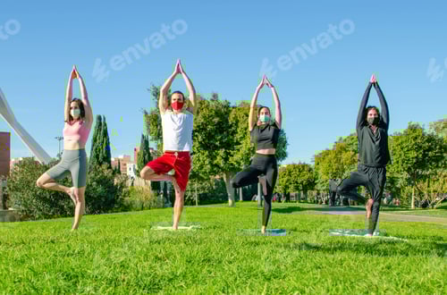 Preview: Closeup shot of friends in facial masks doing yoga in the park - new normal concept