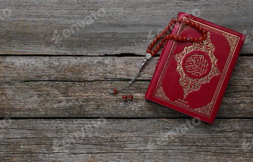 Preview: Muslim prayer beads and Quran on wooden table, top view. Space for text