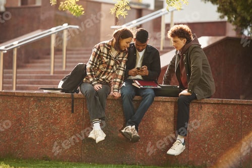 Preview: Three young students in casual clothes are together outdoors