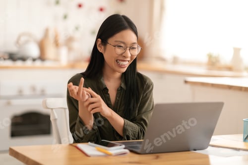 Preview: Happy chinese woman have online meeting, using laptop at kitchen