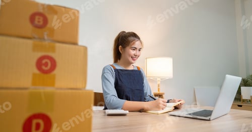 Preview: Young woman working online ecommerce shopping at her shop. prepare parcel box of product for