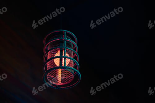 Preview: Loft pendant lamp with red blue glow in steel rebar shade, wooden interior background, copy space