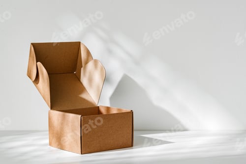 Preview: An open cardboard box rests on a bright white surface with soft shadows highlighting its edges and