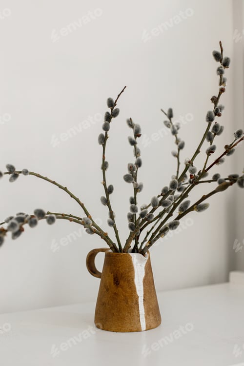 Preview: Willow branches in stylish rustic vase on wooden table. Modern Easter still life