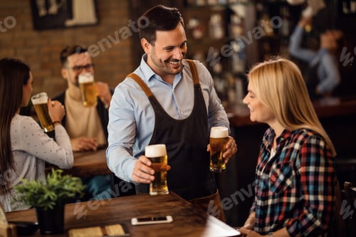 Preview: Happy waiter giving glass of beer to a female guest in a bar.